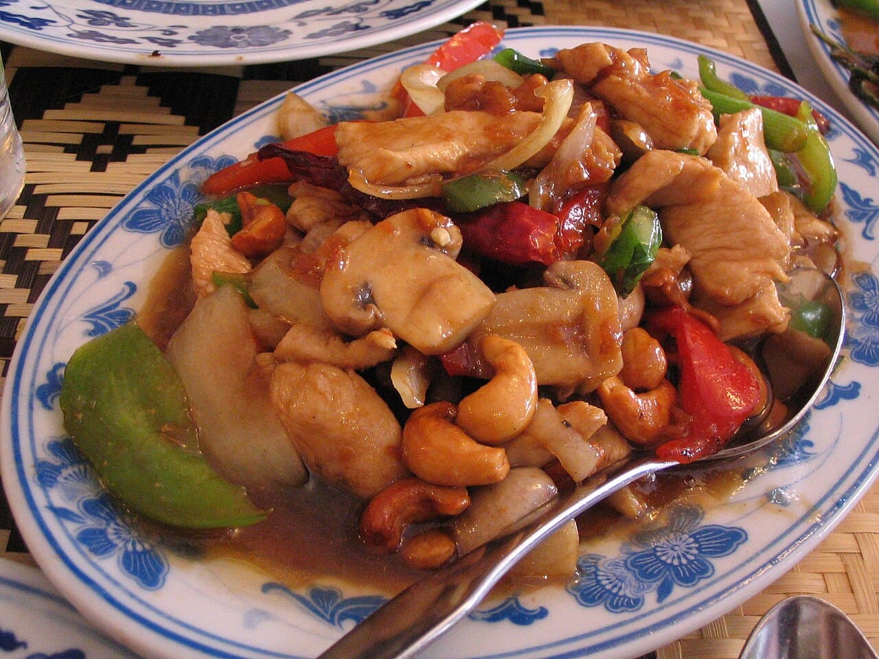 Thai chicken cashew nut stir fry with dried chilies, served on a white plate
