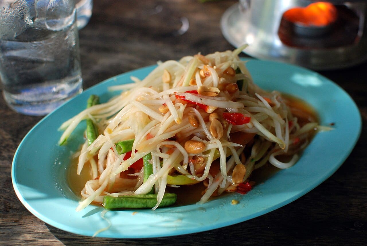 A plate of Thai som tam, a green papaya salad with tomatoes, lime and peanuts